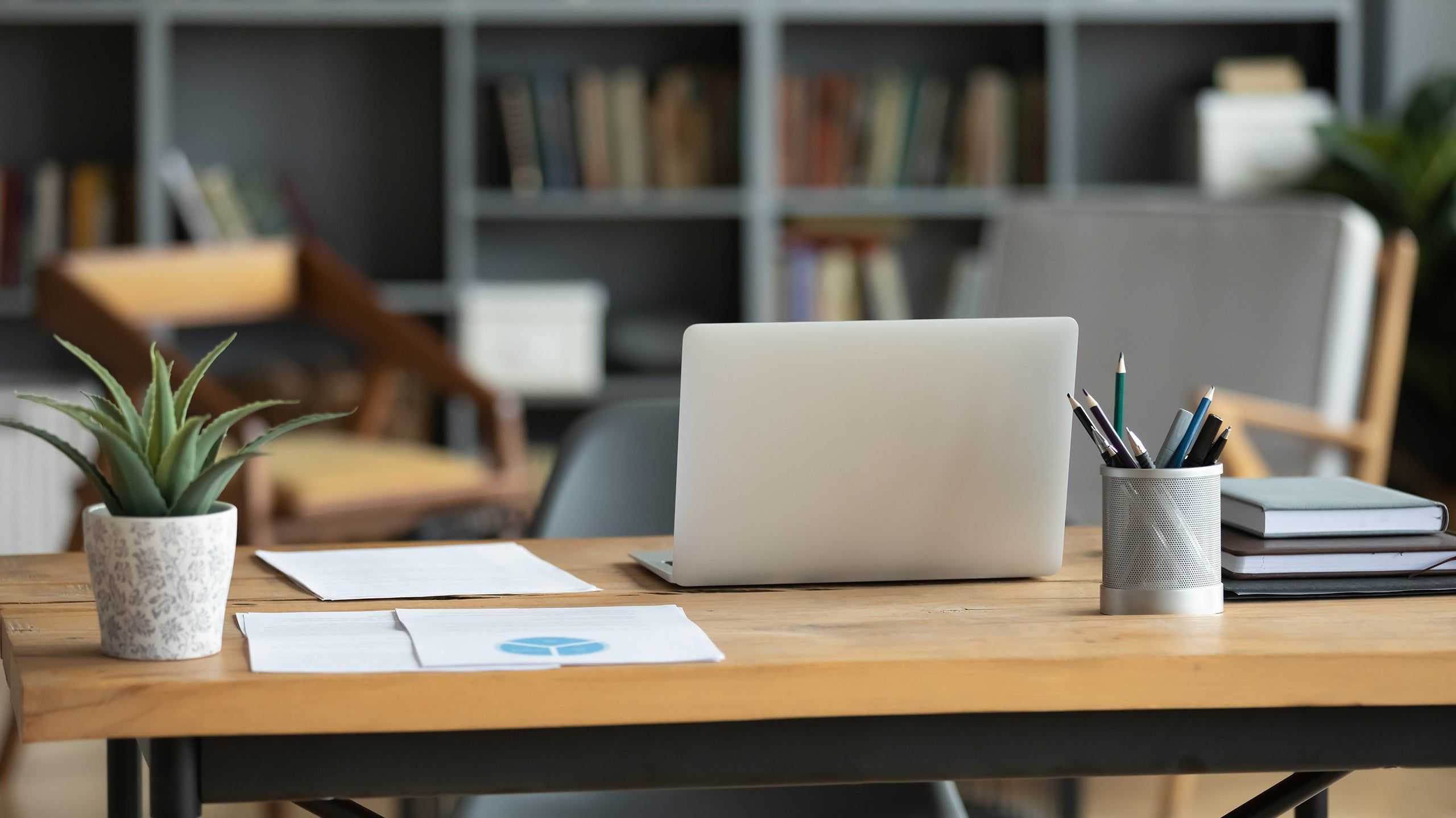 Office with a desk with a laptop and books in the background